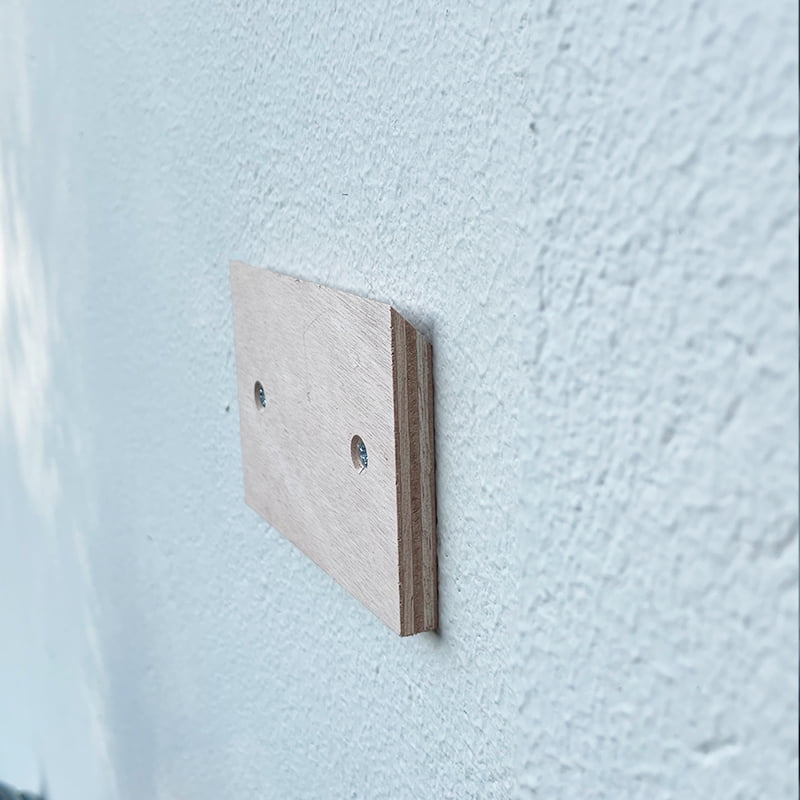 Houten plaatje met schroeven bevestigd aan witte muur