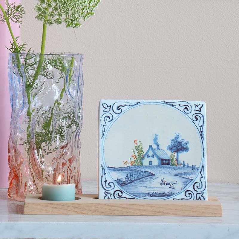 Delftsblauw tegeltje met landschap naast geribbelde glazen vaas