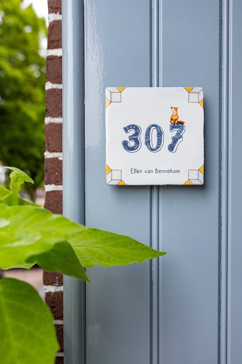 Huisnummer tegeltje met een vosje tegen blauwe muur geplaatst