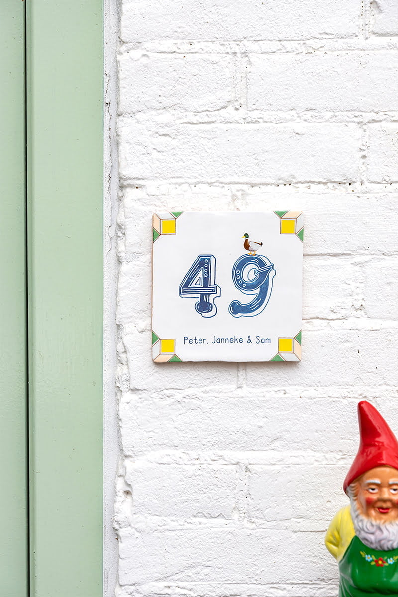 Huisnummer tegeltje met eend op witte bakstenen muur