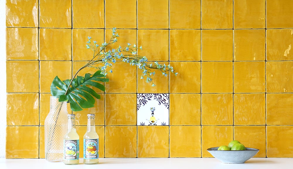 Geel betegeld wand met vaas, drankjes en schaal met fruit