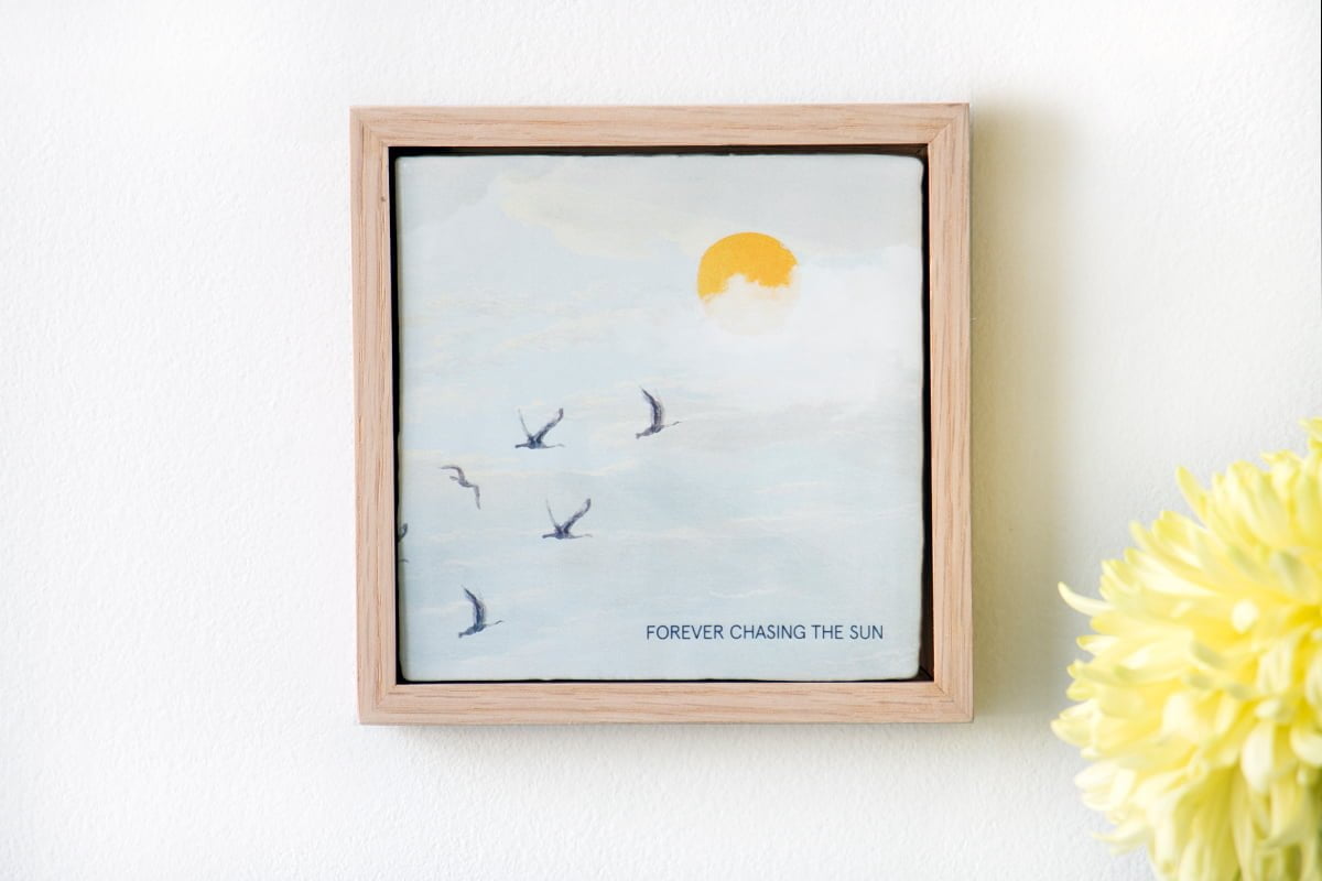 Gepersonaliseerd tegeltje met vogels en zon, aan witte muur