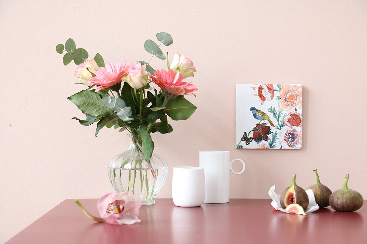 Tegeltje vogel en bloemen boven tafel met bloemenvaas