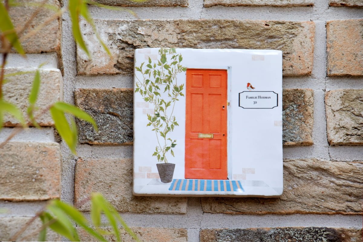 Nieuw huis cadeautegel met voordeur aan bakstenen muur