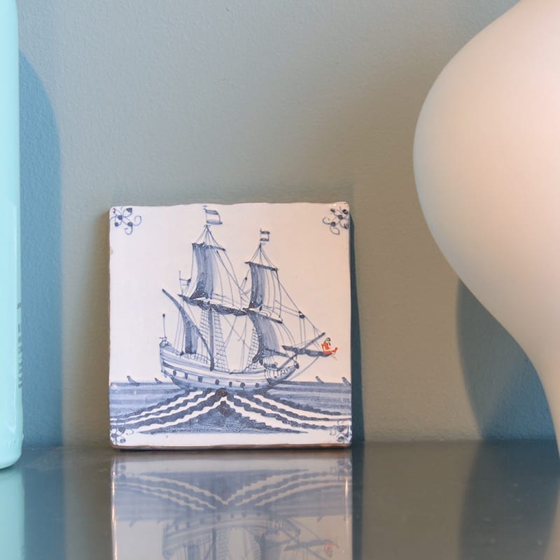 Delfts blauw tegeltje met zeilschip en zeeman in rood