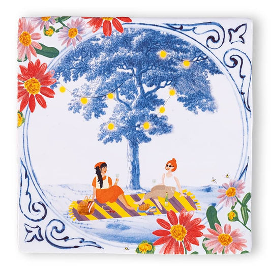Delfts blauw tegeltje met picknick onder boom en bloemenrand
