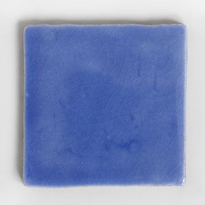 Blauw geglazuurd tegeltje met subtiele craquelé op witte achtergrond