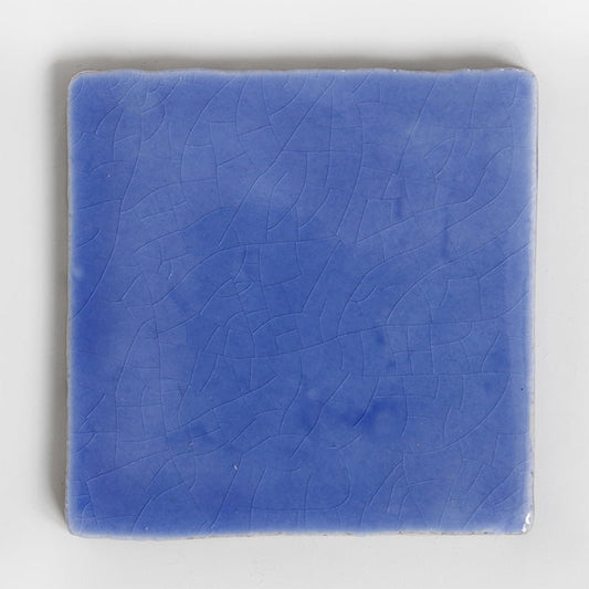 Blauw geglazuurd tegeltje met subtiele craquelé op witte achtergrond