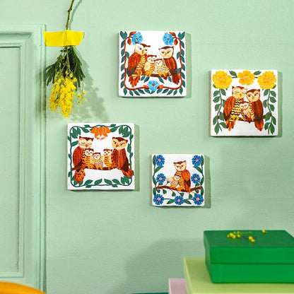 Geboortetegeltjes met uilen aan groene muur hangen linksboven bloem