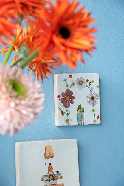 Tegeltjes met bloemen en omhelzend paar tegen blauwe muur