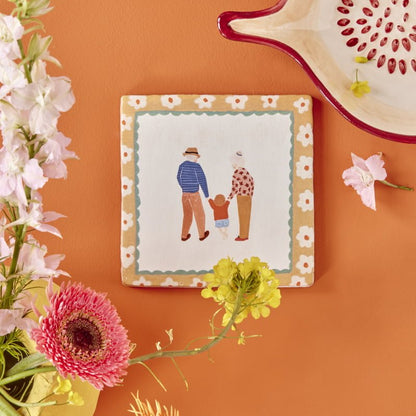 Tegeltje gezinswandeling tegen oranje muur met bloemen en schaal