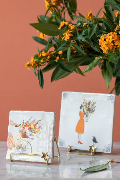 Gouden tegelhouder met bloemmotief tegen een oranje achtergrond