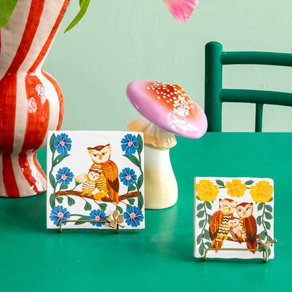 Geboortetegeltje met uilen en bloemen, geplaatst op groen oppervlak