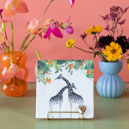Tegeltje met giraffen, omlijst door bloemen en bladeren
