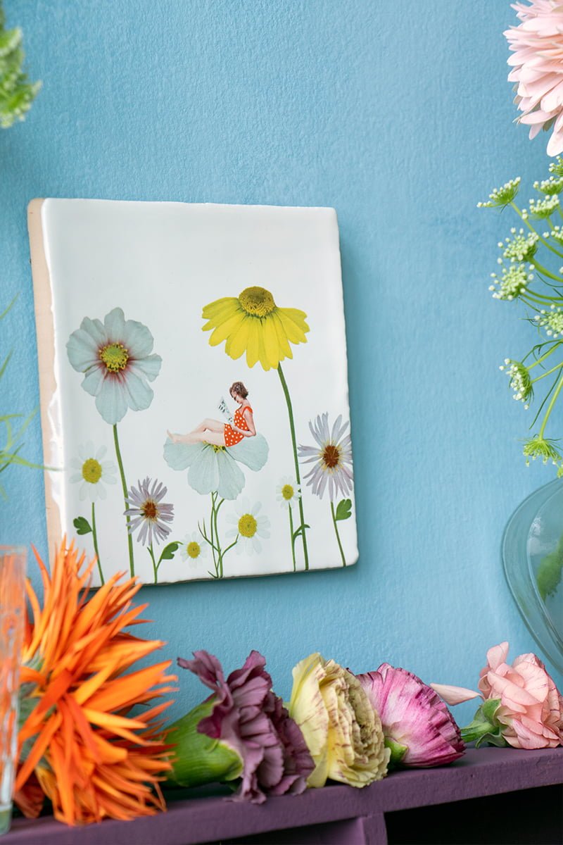 Tegeltje bloemenmeisje op blauwe muur versierd met bloemen