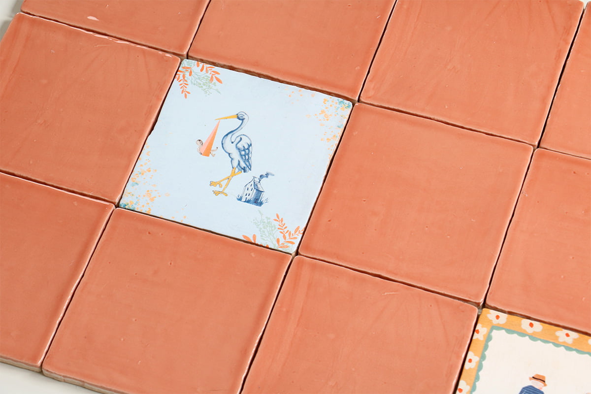 Blauw vierkantje met witte ooievaar tussen terracotta tegels geplaatst