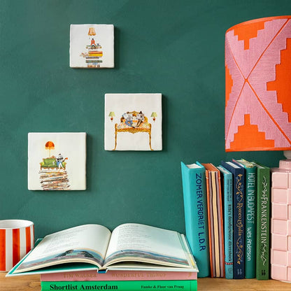 Huwelijkscadeau tegeltjes met boeken thema, weergegeven op groene muur