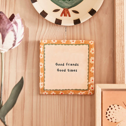 Gepersonaliseerd tegeltje met tekst, hangt aan houten muur