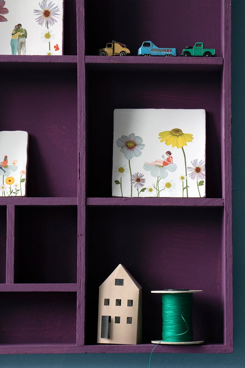 Tegeltje vrouw bloemmotief boekenplank met speelgoedautootjes en miniatuurhuisje