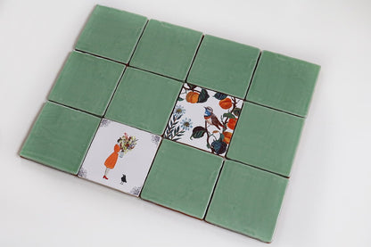 Groene tegels met illustraties van vrouw en vogelmotieven in midden