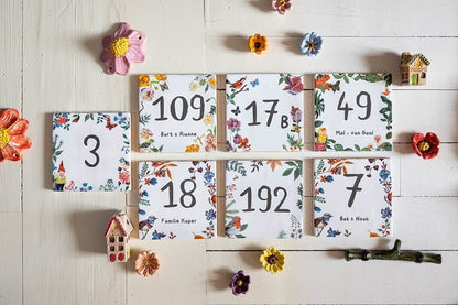 Huisnummer tegeltje met bloemen en vogeltjes op houten tafel