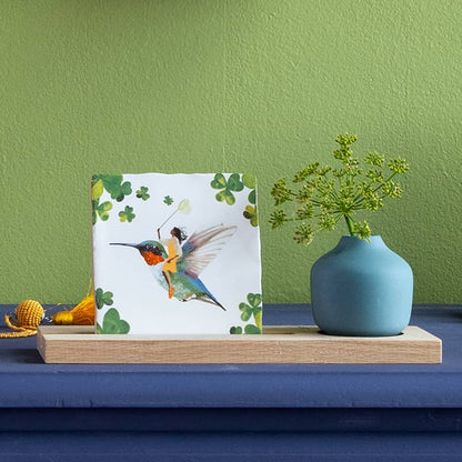 Tegeltje met elfje op vogel, geplaatst naast blauwe vaas