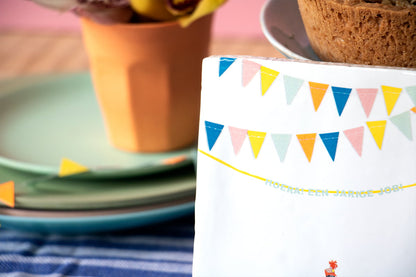Gepersonaliseerd tegeltje met kleurrijke vlaggetjes, omgeven door servies