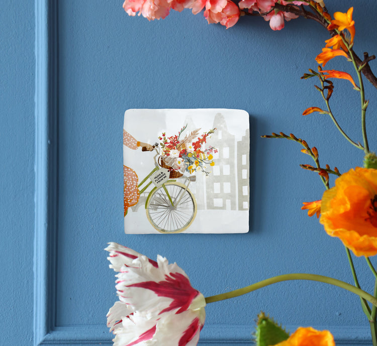 Gepersonaliseerd tegeltje met fiets en bloemen, op blauwe muur