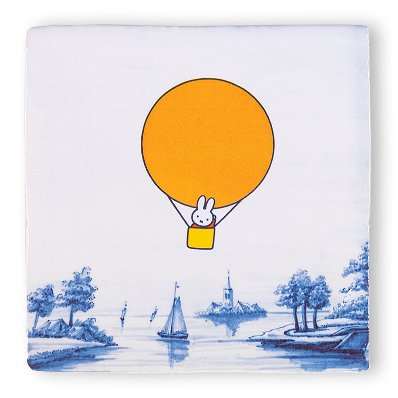 Tegeltje met nijntje in een oranje luchtballon zwevend boven Delfts Blauw landschap