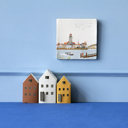 Tegeltje Deventer boven gekleurde huisdecoraties tegen blauwe wand
