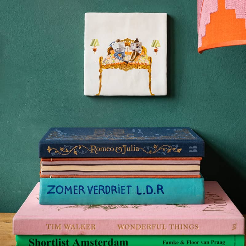 Huwelijkscadeau of liefdescadeau tegeltje met illustratie bed met lezend koppel, opgehangen boven gestapelde boeken 