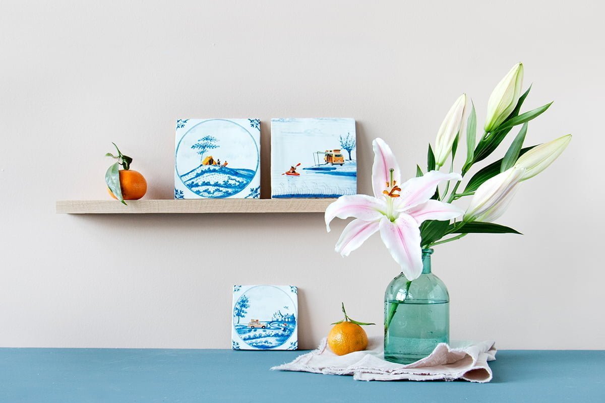 Delfts blauwe StoryTiles tegeltjes met natuurmotieven, gepresenteerd op houten plank