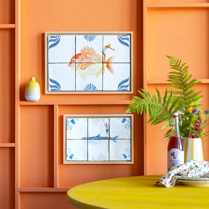 Twee StoryTiles tegeltableaus aan een oranje wand opgehangen. 