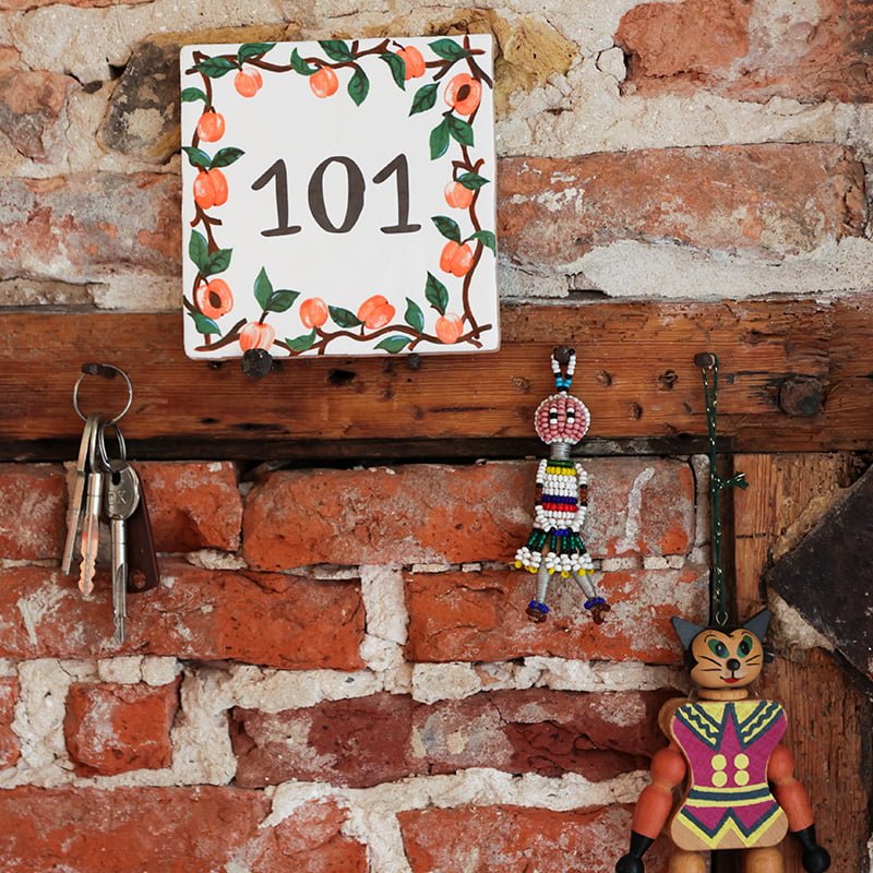 Huisnummer tegeltje met abrikozen aan bakstenen muur