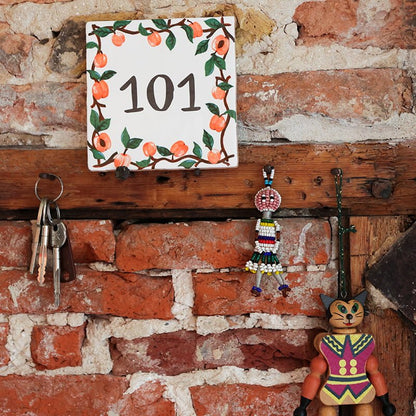 Huisnummer tegeltje met abrikozen aan bakstenen muur