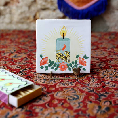 Tegeltje met kaars, bloemen en tijger op tafelkleed