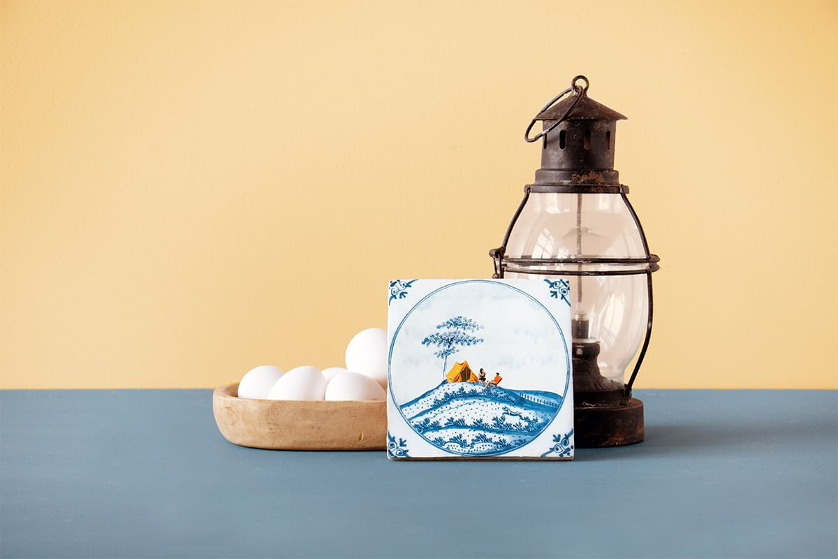 Delfts Blauw tegeltje met campingafbeelding, naast een lantaarn geplaatst