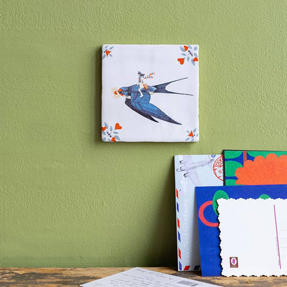 StoryTiles tegeltje met blauwe vogel met envelopje in zijn snavel op groene muur
