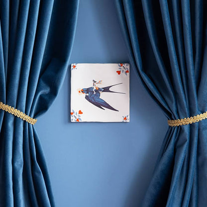 Gepersonaliseerd tegeltje met zwaluw, tussen blauwe gordijnen geplaatst