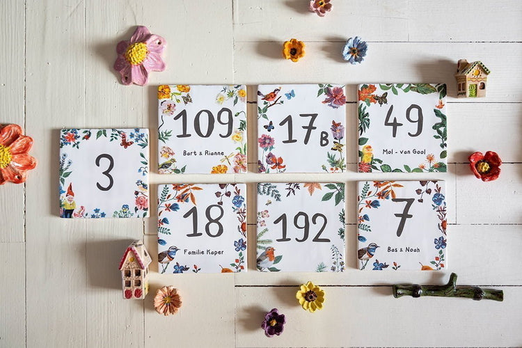 Huisnummer tegeltje met bloemen en vogeltjes op houten tafel