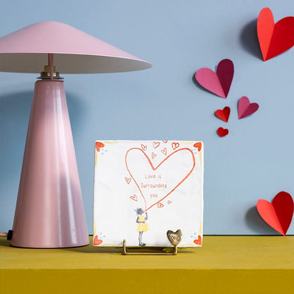 Tegeltje met hartjes op kastje naast roze lamp