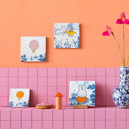 Geboortetegel met illustraties tegen roze muur met bloemenvaas