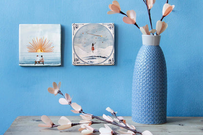 Delfts blauwe tegeltjes met gouden details met illustraties op blauwe muur gepresenteerd