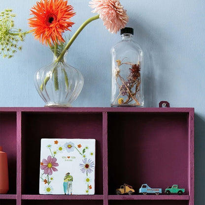 Tegeltje met bloemen en namen en huwelijksdatum op paarse plank