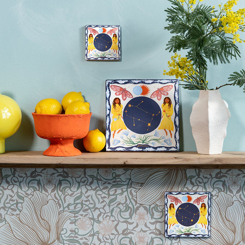 sterrenbeeldtegels gemini in drie maten op een wandplank en aan een lichtblauwe muur gepresenteerd