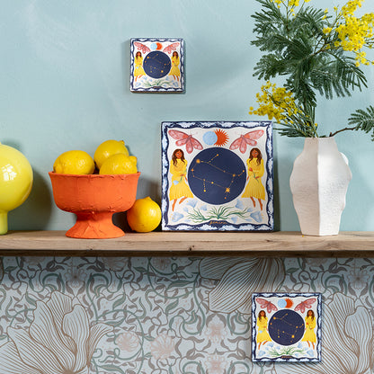 sterrenbeeldtegels gemini in drie maten op een wandplank en aan een lichtblauwe muur gepresenteerd