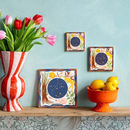 Geboortetegeltje sterrenbeeld Boogschutter kleurrijk aan lichtblauwe muur met bloemen