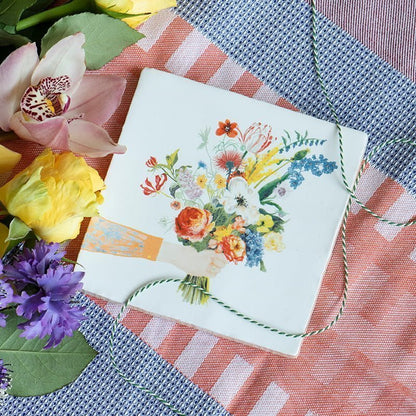 Bloemenegeltje met boeket bloemen op gekleurde stoffen achtergrond