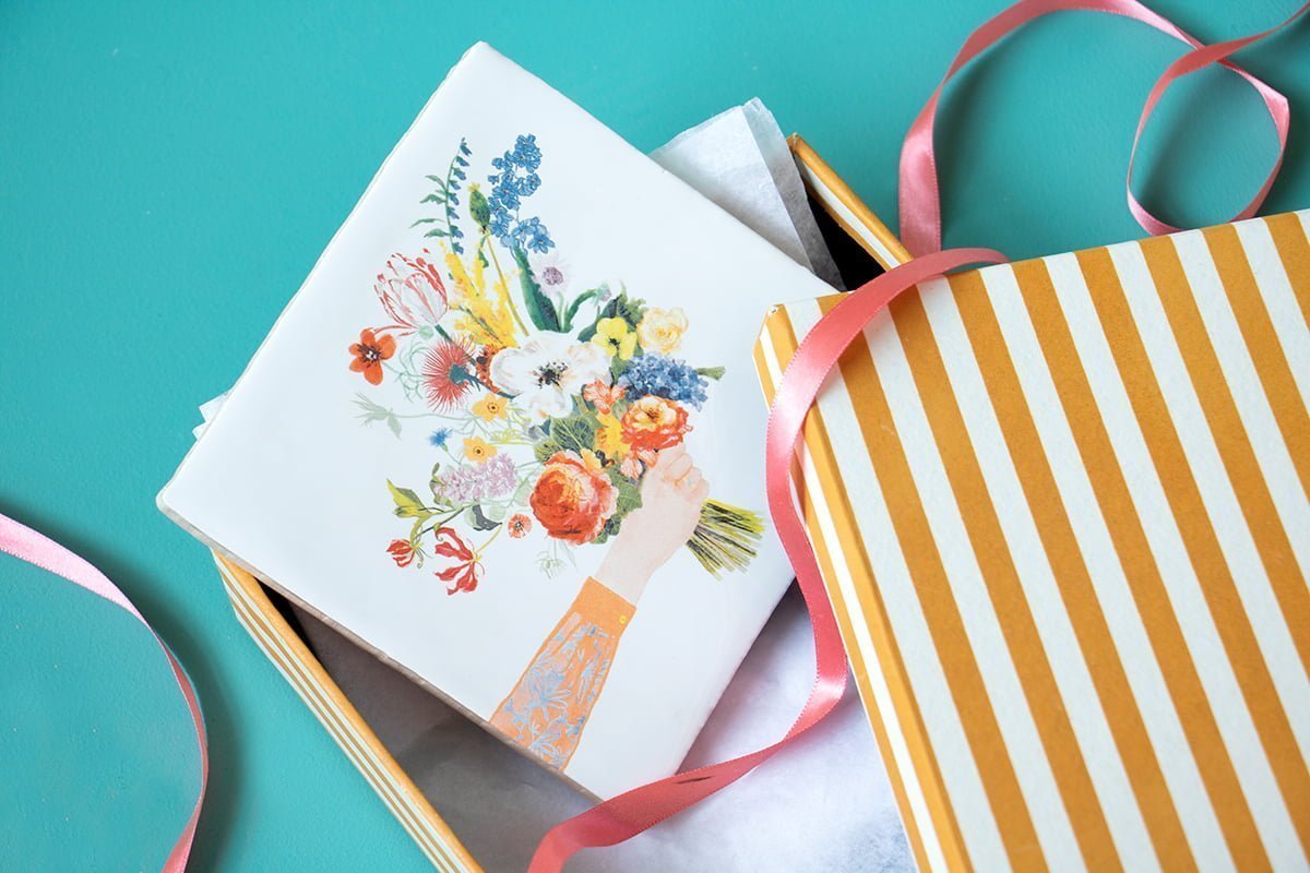 Tegeltje met bloemenboeket in gestreepte geschenkdoos gepresenteerd