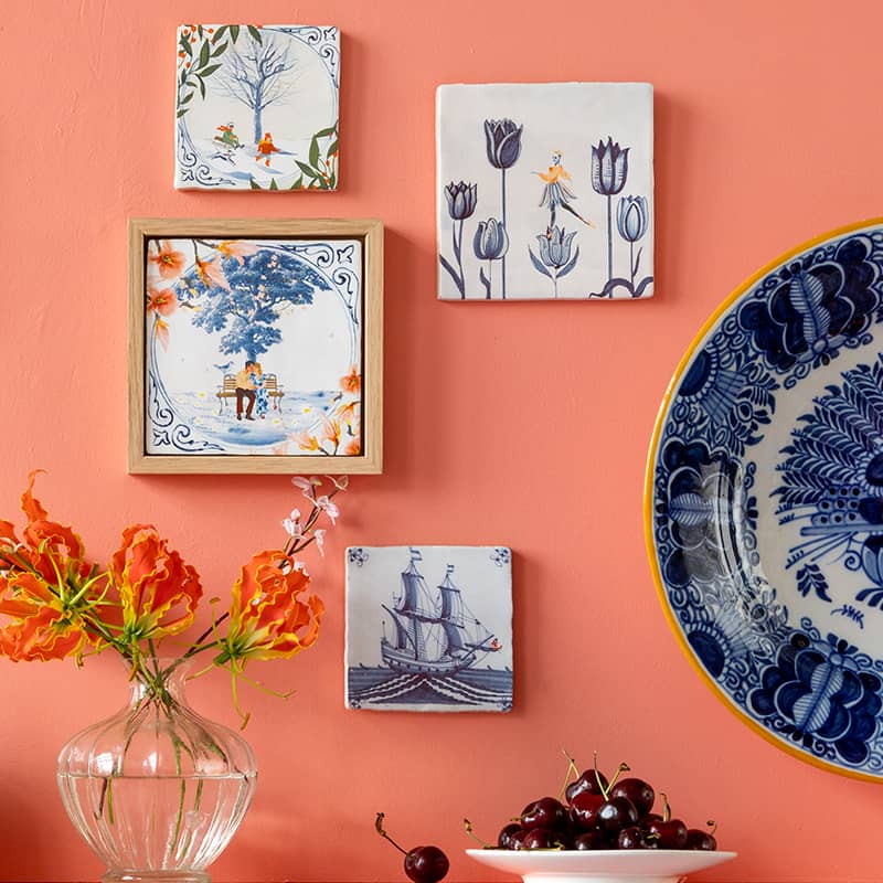 Delfts blauwe tegeltjes met bloemen en zeilschip aan roze muur